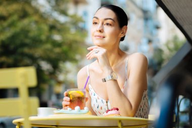 Gülümseyen ve limonata yudumlarken mesafe içine bakarak sakin kişi