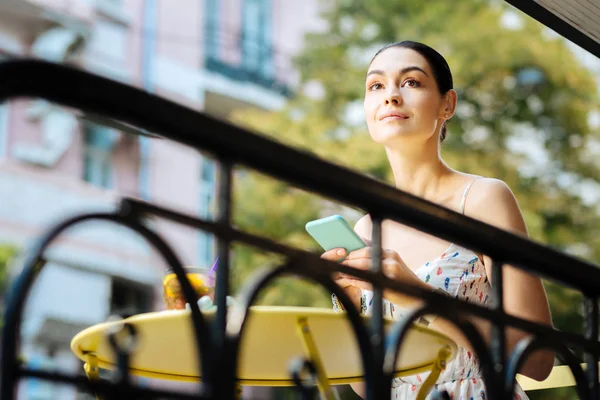 Mujer pacífica con un teléfono inteligente buscando calma y sonriendo — Foto de Stock