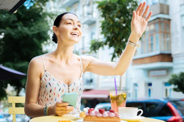 Glückliche Frau winkt mit der Hand, während sie einen Freund bemerkt — Stockfoto