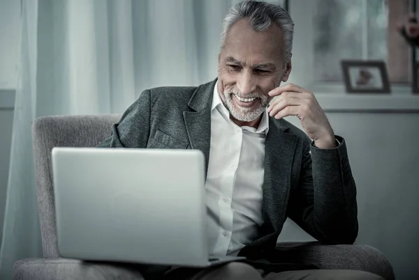 Fröhliche grauhaarige männliche Person, die auf den Computer schaut — Stockfoto