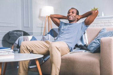 Kanepede oturan gülümseyen adam.