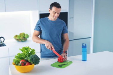 Vejetaryen mutfakta ayakta ve bir biber kesme gülümseyen