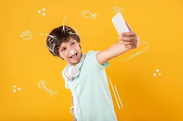 Rapaz positivo a fazer caretas enquanto tira uma selfie — Fotografia de Stock
