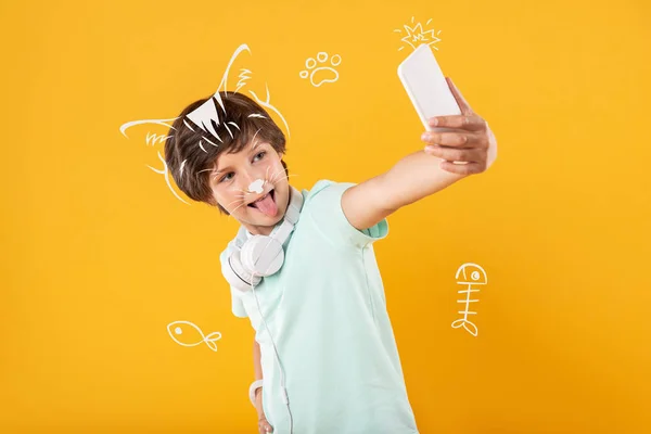 Alegre chico tomando selfies y mostrando su lengua a una cámara — Foto de Stock