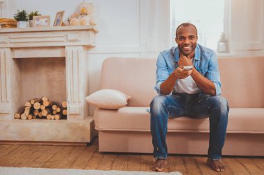 Gülümseyen adam elinde bir uzaktan kumanda