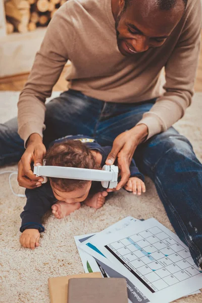 Papi sonriente poniendo auriculares en la cabeza de sus hijos — Foto de Stock