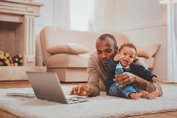 Ernstige man werkt en zijn kind babysit — Stockfoto