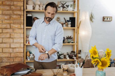 İş için hazırlanıyor el saatini kapalı alarak esmer el işleri ustası