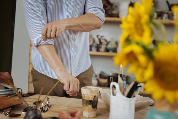 Homme à tout faire portant une chemise rayée debout près de sa table de travail en bois — Photo
