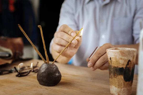 Man wearing striped shirt burning little aroma sticks — Stock Photo, Image