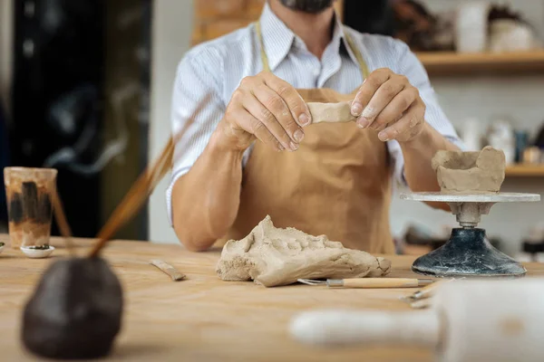 Bärtiger Handwerker, der in der Nähe der Töpferscheibe Tonstreifen formt — Stockfoto