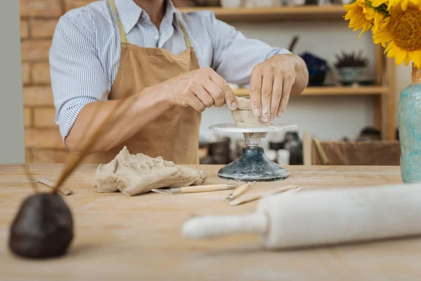 Ceramista usando jigger cerámica de pie cerca de jarrón con girasoles — Foto de Stock