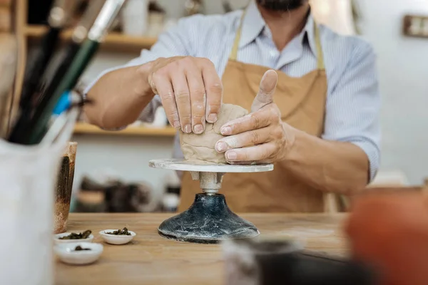 Ervaren potter dragen schort zitten in de buurt van aardewerk wiel — Stockfoto