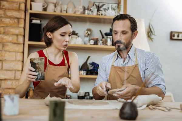 Dark-haired woman asking questions during ceramics master class