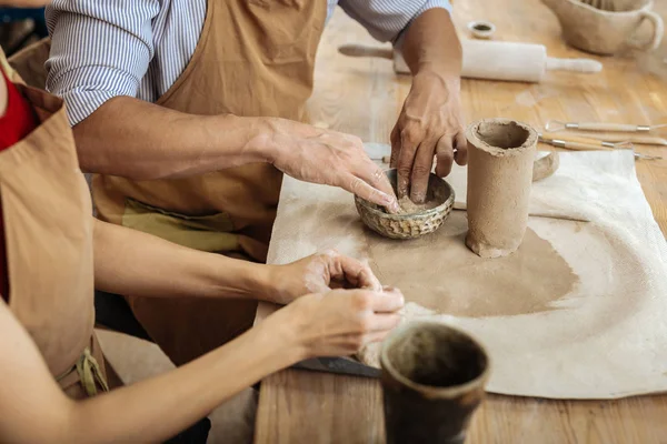 Сильний зрілий чоловік у смугастій сорочці робить предмети глиняного посуду — стокове фото