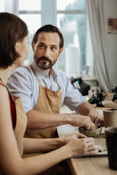 Dunkeläugiger Keramiker im Gespräch mit seiner Frau während der Arbeit — Stockfoto