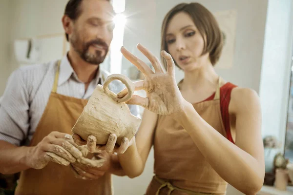 Ceramista femenina de cabello oscuro mejorando su futura taza de té — Foto de Stock