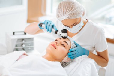 Güzel yetenekli kadın dermatolog bir dermatoscope holding