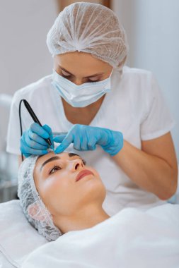 Ciddi yetenekli kadın dermatolog bir köstebek kaldırma