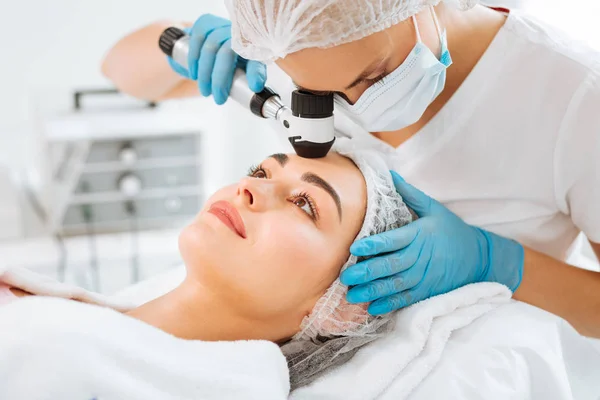 Aangename jonge vrouw die haar huid gecontroleerd — Stockfoto