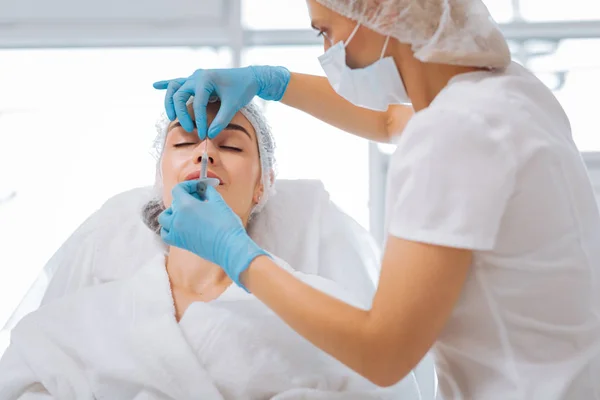 Professionell utbildad kosmetolog röra hennes klienter näsa — Stockfoto
