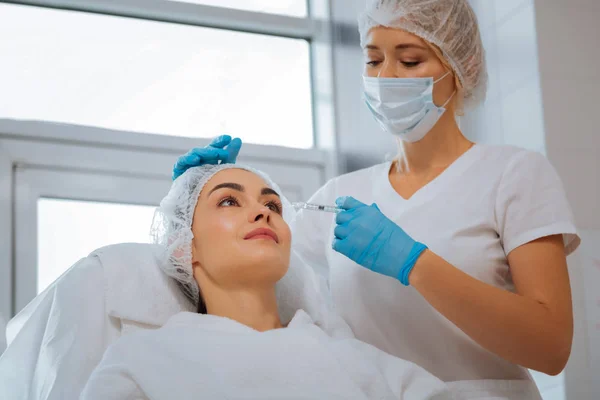 Professionella kvinnliga kosmetolog tittar på hennes klient — Stockfoto
