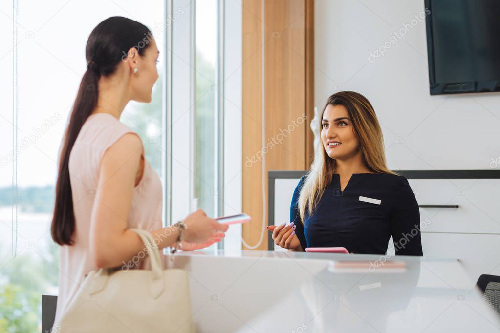 Nice pleasant woman taking to the receptionist