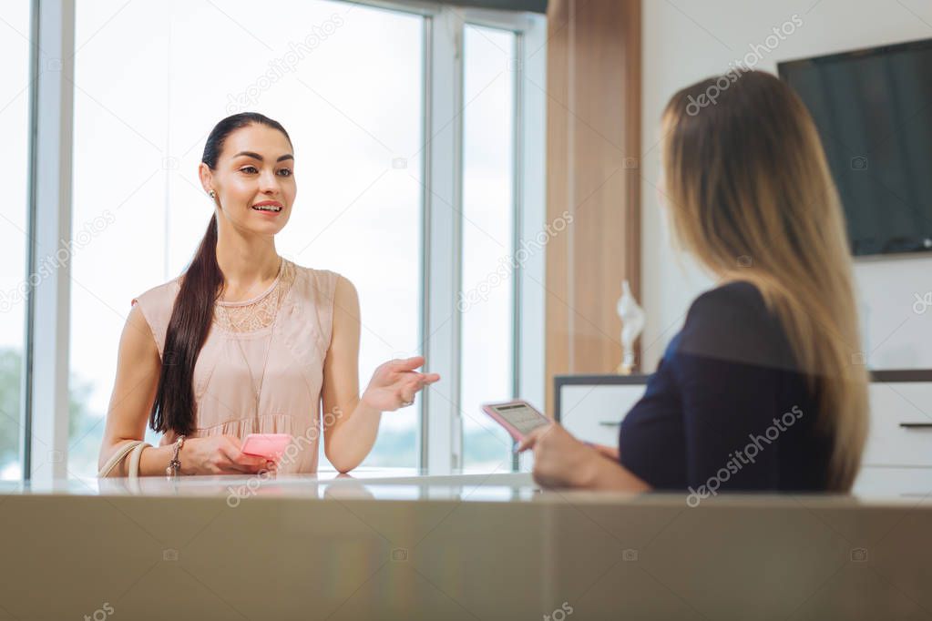 Joyful pleasant woman talking to the administrator