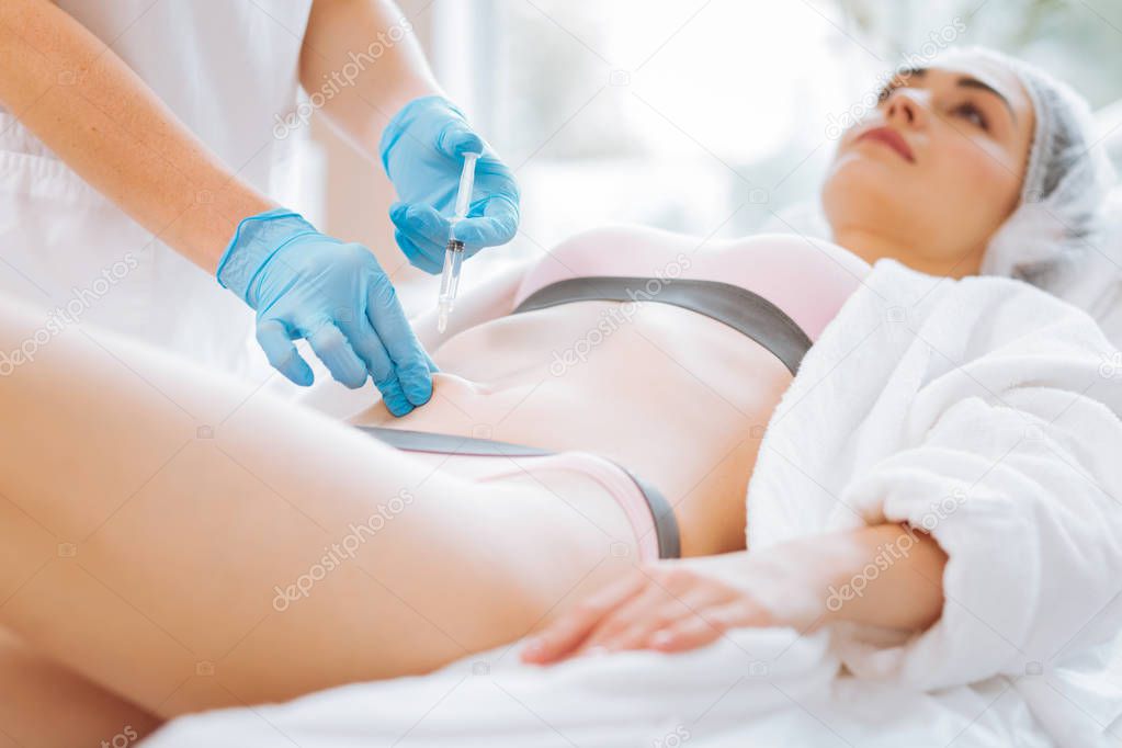 Skilled professional beautician doing a body injection