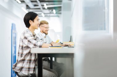 Neşeli erkekler alan coworking içinde dizüstü bilgisayarlarda çalışırken gülümseyen