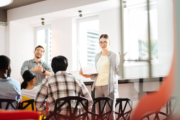 Веселые молодые ораторы улыбаются аудитории во время проведения семинара
