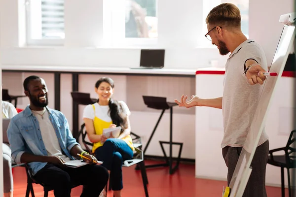 Professeur positif pointant vers le tableau à feuilles mobiles et souriant à ses élèves — Photo