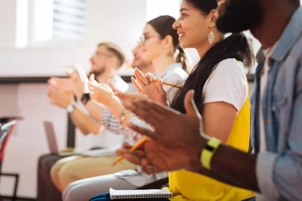 Confident students sitting in a row and smiling while applauding — Stock Photo, Image