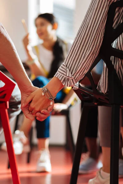 Close up of two people sitting and holding hands — Stock Photo, Image