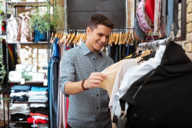 Güzel T shirt bakarken gülümseyen pozitif genç adam