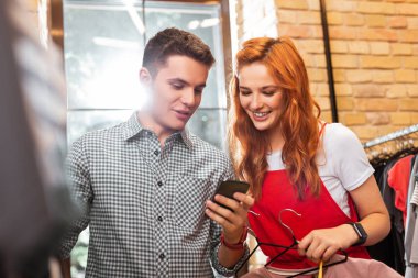 Duygusal çift gülümseyen ve akıllı telefon ekranına bakarak