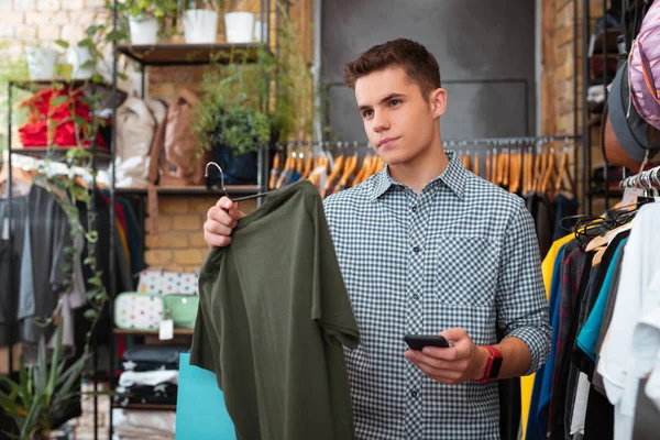 Yeşil tişörtlü tutarak ve fiyatı hakkında düşünme sakin adam