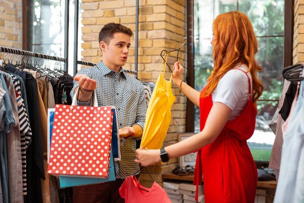 Νεαρό ζευγάρι κάνει ψώνια και την συζήτηση πολύχρωμα ρούχα — Φωτογραφία Αρχείου