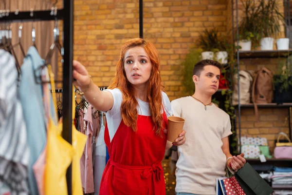 Ung man såg trött och flickvännen galen röra kläder i butik — Stockfoto
