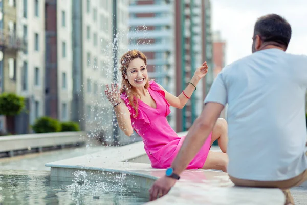 Счастливая привлекательная женщина играет с водой в фонтане — стоковое фото