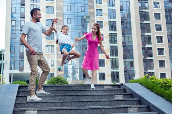 Pais positivos felizes segurando suas filhas mãos — Fotografia de Stock