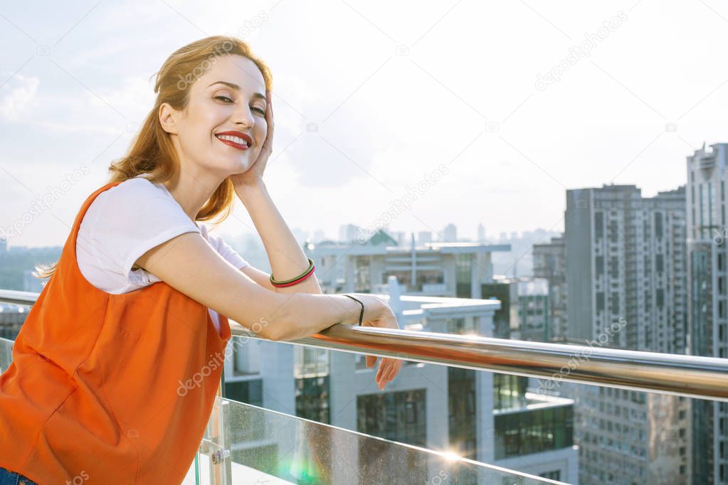 Joyful positive woman standing on the balcony