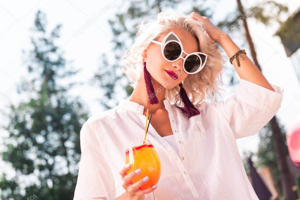 Summer rest. Joyful beautiful woman holding a cocktail while relaxing during her vacation