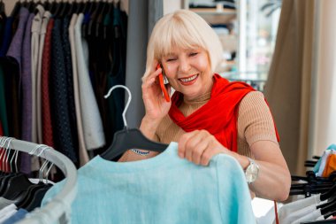 Memnun gri saçlı kadın alışveriş mağazasında arkadaşı ile konuşurken