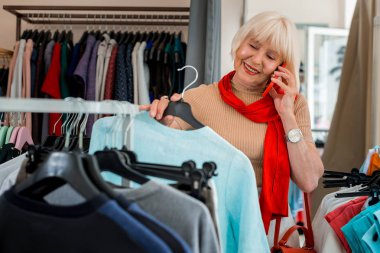 Memnun sevimli yaşlı kadın alışveriş sırasında cep telefonu üzerinden bir konuşma olan