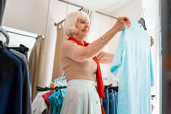 Blij ouderen vrouw bewonderen zomer jurk in kledingwinkel — Stockfoto