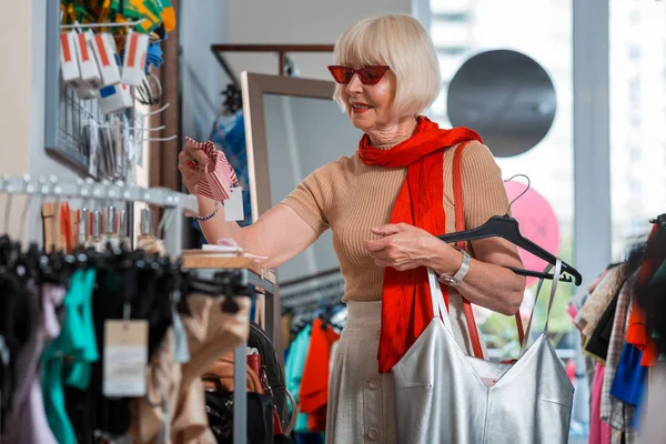 Konsentrert eldre kvinne som velger et fint pannebånd – stockfoto