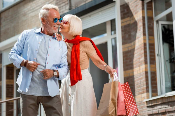 Adorável mulher de cabelos grisalhos beijando seu marido na rua — Fotografia de Stock