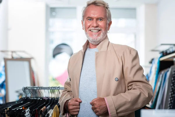 Bonito cinza cabelos homem tentando novo jaqueta no — Fotografia de Stock