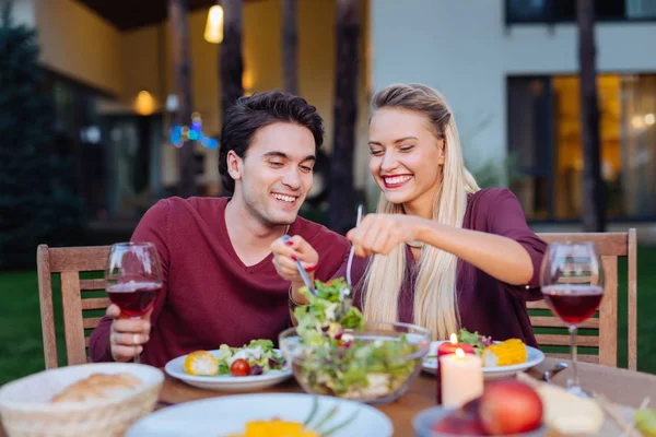 Casal feliz encantado que serve a salada um a outro — Fotografia de Stock